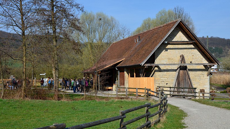 Ein historischer Schafstall, daneben einige Besucher:innen