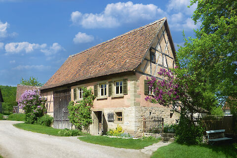 Rosa verputztes Wohnhaus mit intergrierter Scheune und Garten, als Fachwerkbau