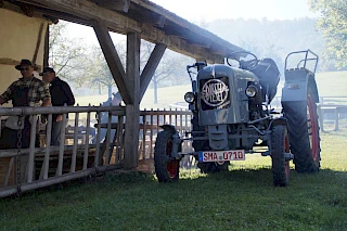 Ein historischer Traktor steht neben einem Vordach