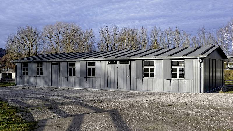 Graue Zwangsarbeiterbarracke an einem Schotterweg