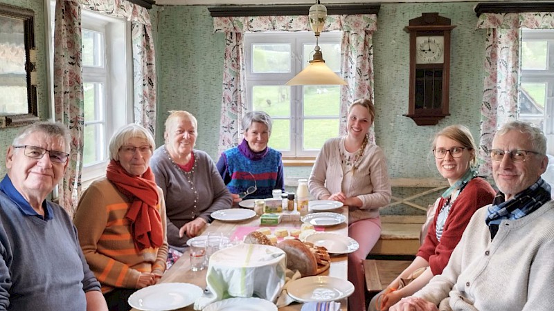 Projektanleiter:innen sizten gemeinsam an einem gedeckten Tisch in der Stube der Mühle aus Weipertshofen