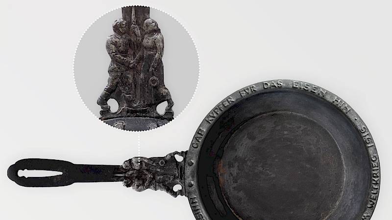 Eisenpfanne mit Umschrift auf dem Rand und figürlicher Verziehrung am Stiel